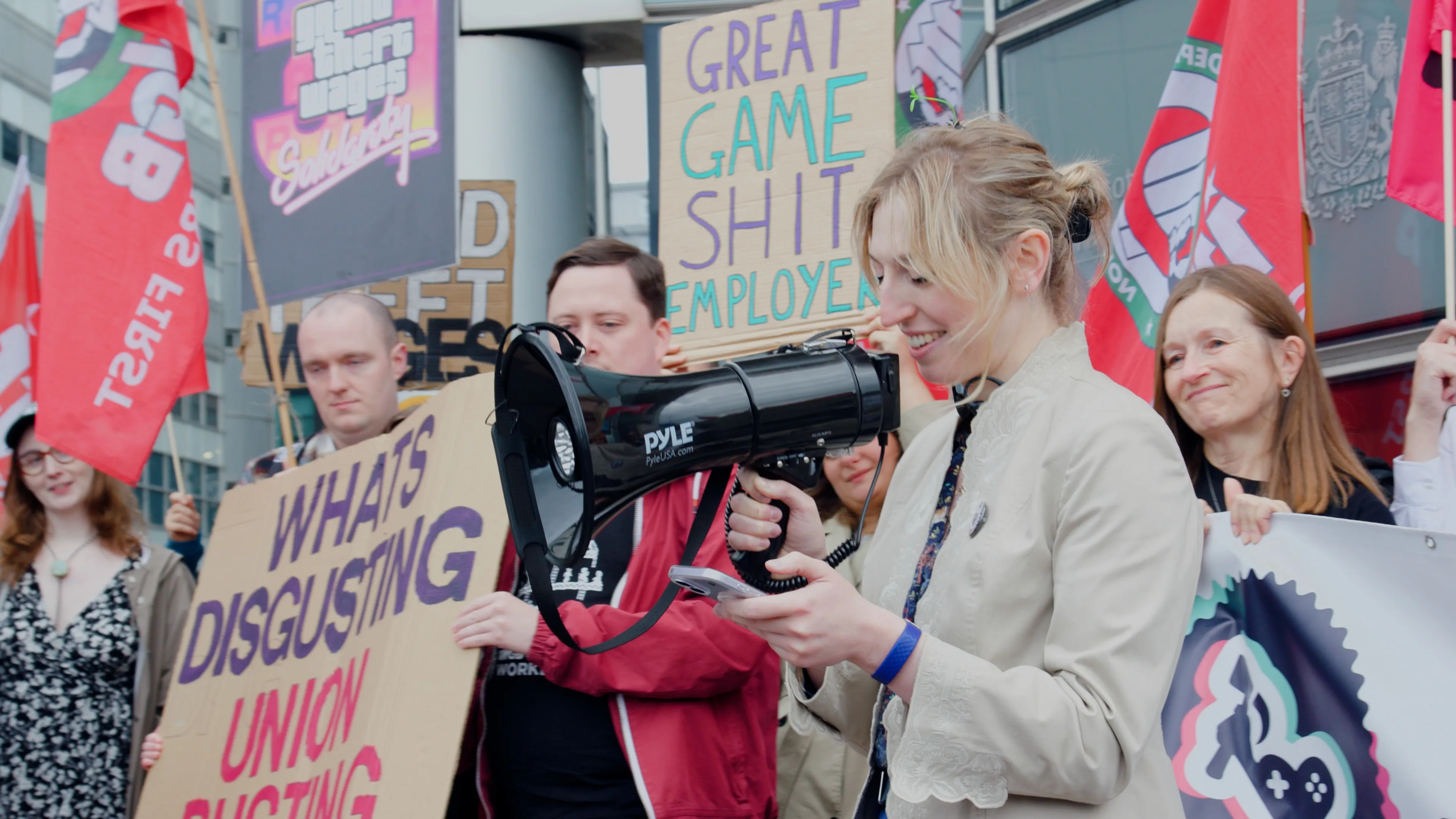 A demonstrator holds a megaphone among IWGB flags outside the Glasgow employment tribunal.